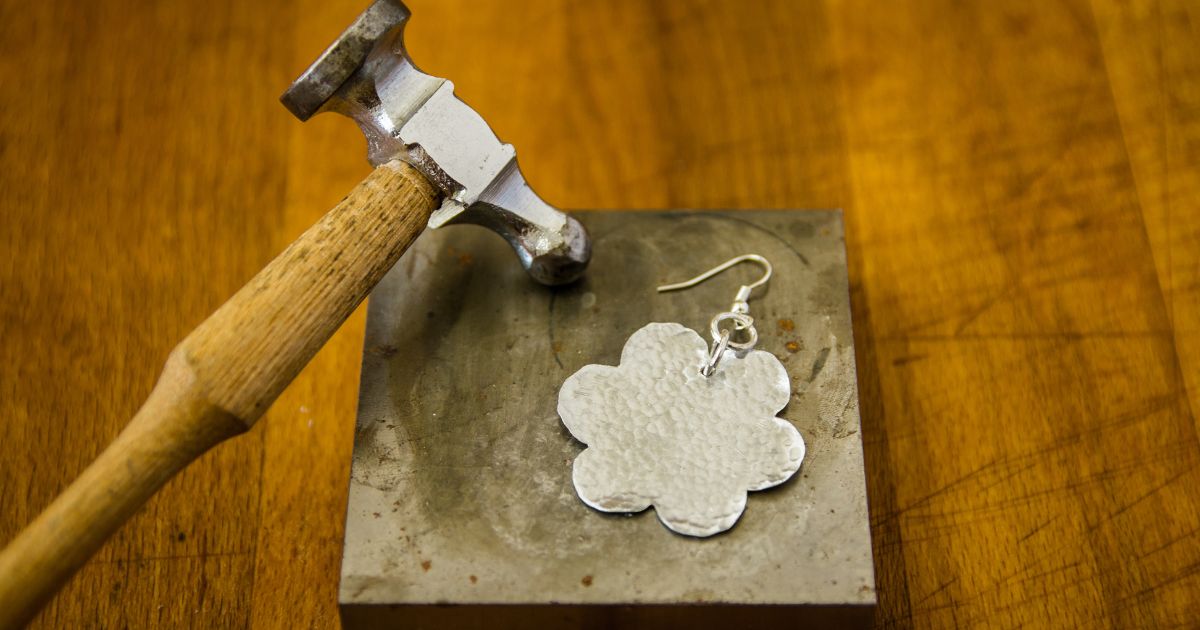 Metalwork with a hammer and a flat metal flower shape 